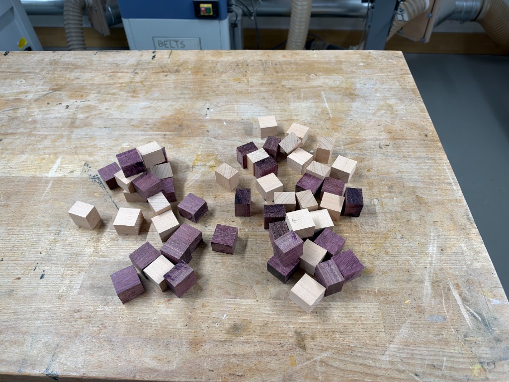 A pile of cut beech and purpleheart blocks on the workbench