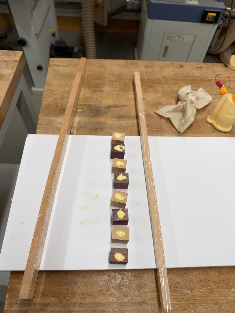 Linear strip of wood blocks with glue dabs between guide runners