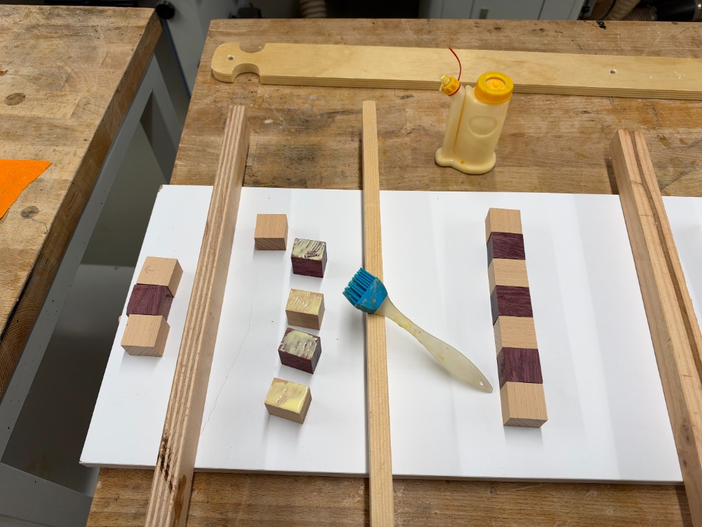Silicone brush spreading glue across alternating wood blocks